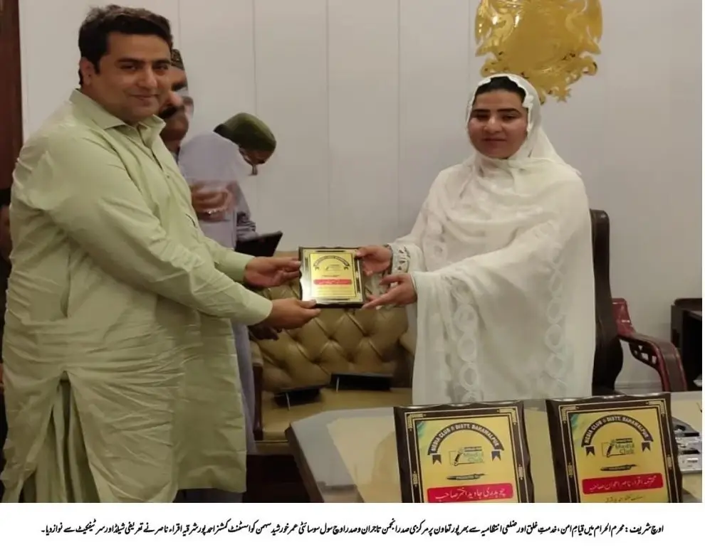 "Assistant Commissioner Iqra Nasir presents commemorative shield to Central President Anjuman Tajran Umar Khurshid Sahman"